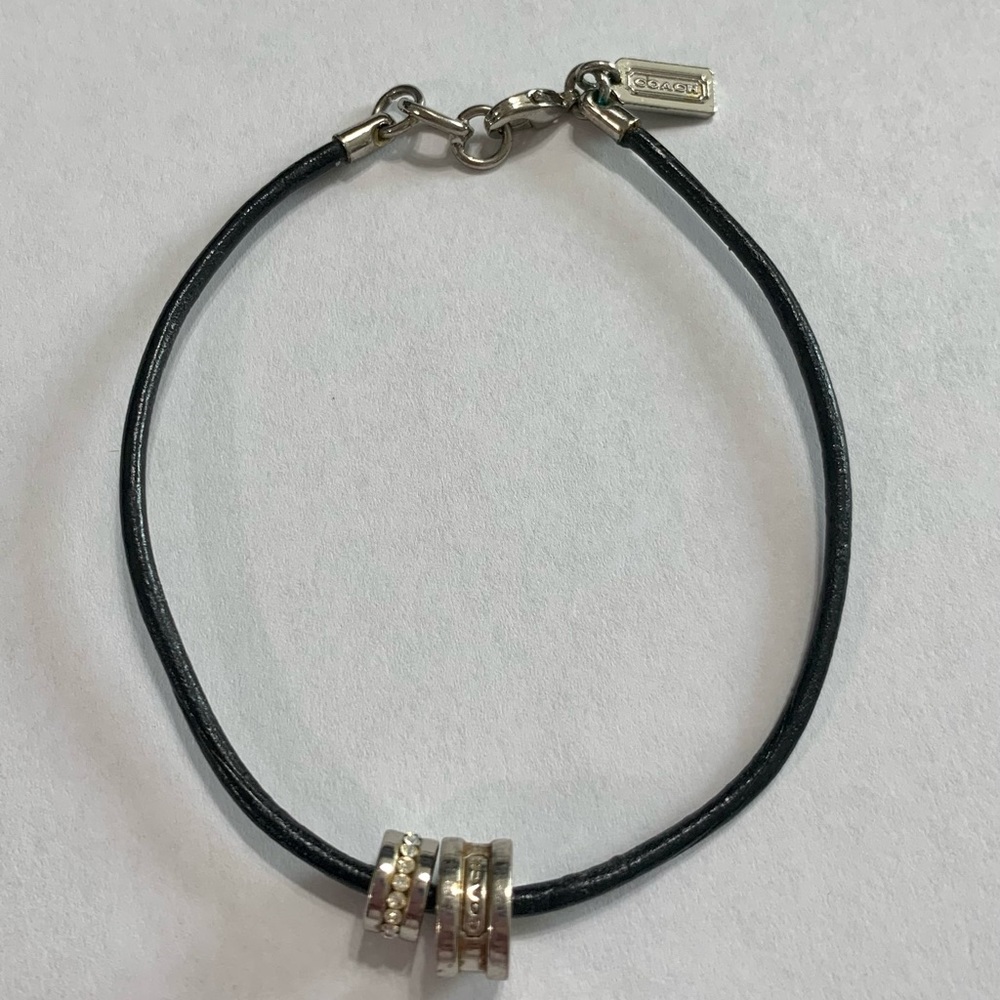 Coach black leather bracelet with 2 charms.